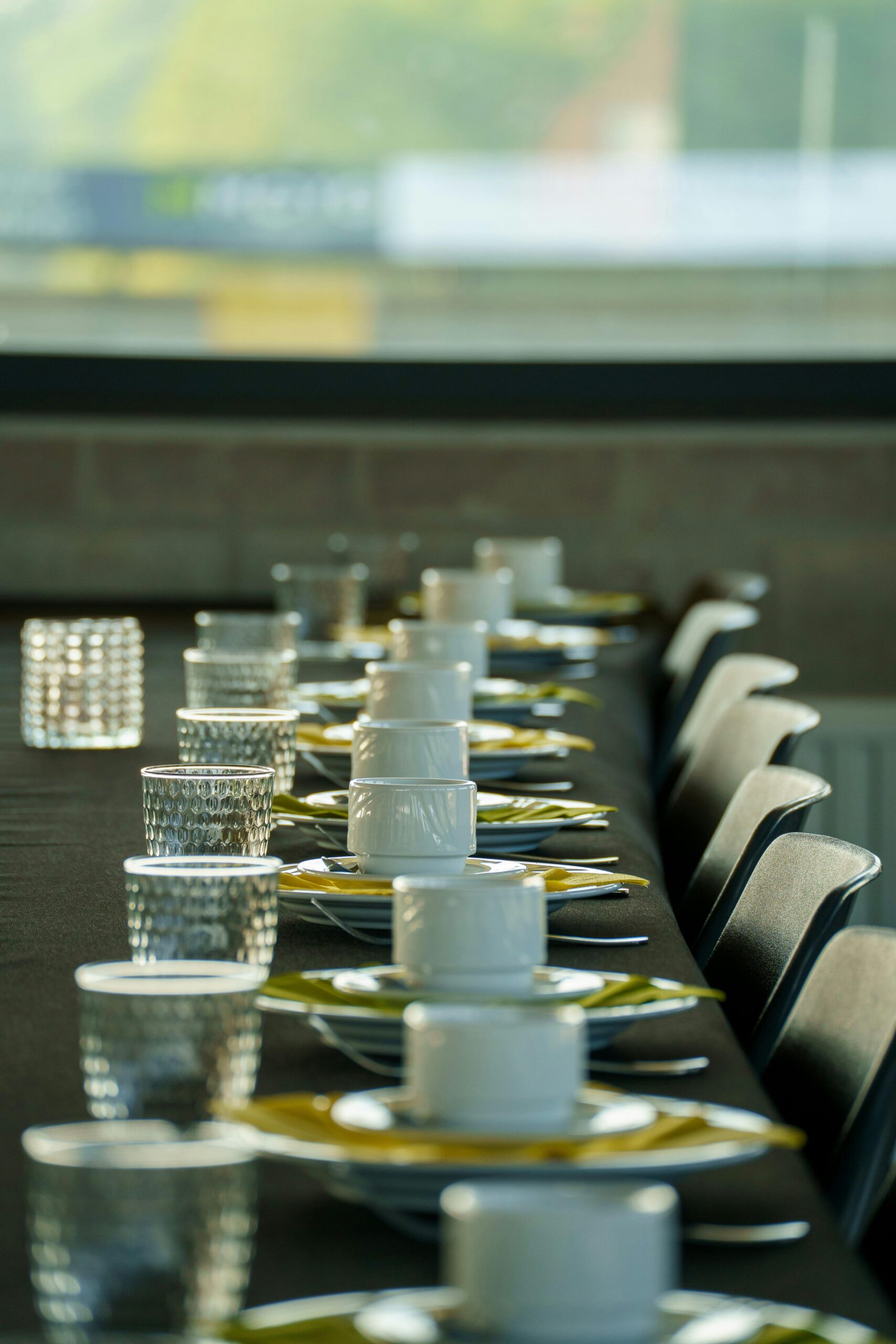 Long table elegantly set with white porcelain dishes and glassware, creating a luxurious dining ambiance.